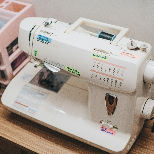 A sewing machine sits on top of a desk, ready for the first sewing project of a beginner.