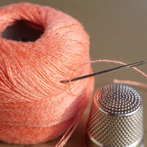 A roll of thread and aneedle on a table-perfect for beginners learning to sew!